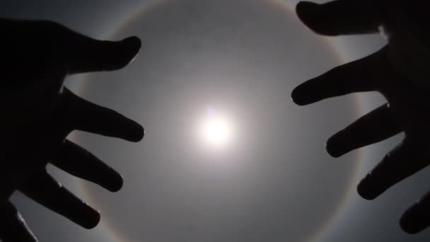 Vista aérea del sol con un arco iris circular rodeado de cielos brillantes y nubes blancas con sombras de manos extendidas. Fenómeno, halo solar. Fondo natural en movimiento. - Metraje, vídeo