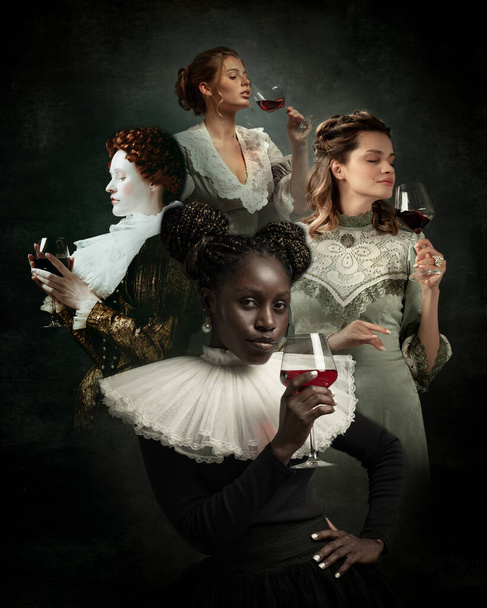 Degustation. Adorable young women as medieval royalty persons in vintage outfits tasting wine on dark background. Concept of comparison of eras, modernity and renaissance, baroque style. Creative - Fotó, kép
