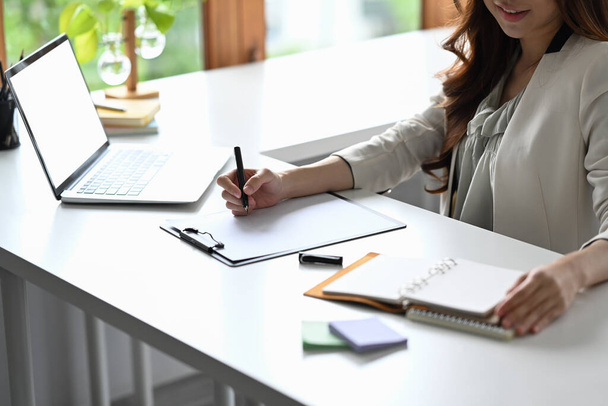 Millennial female entrepreneur sitting other workplace and signing document. - Fotografie, Obrázek