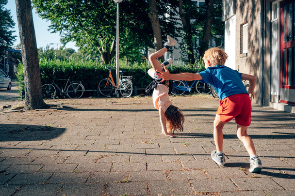 children playing on the neighborhood sidewalk - girl doing cartwheel - Φωτογραφία, εικόνα