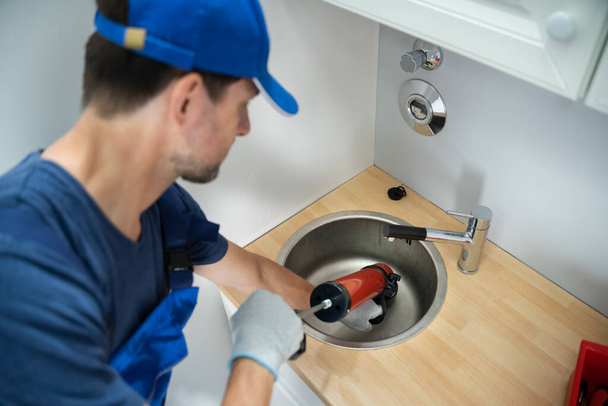 Plumber Cleaning Drain And Sink Using Pump - Foto, Imagen