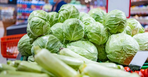 Young cabbage ans zucchini in shop. Green vegetables sold on grocery market. Natural organic veggies at supermarket. Vegetarian healthy nutrition - Фото, изображение