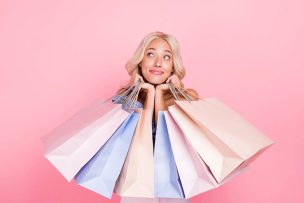Photo of dreamy adorable girl dressed blue top holding bargains looking empty space isolated pink color background. - Zdjęcie, obraz