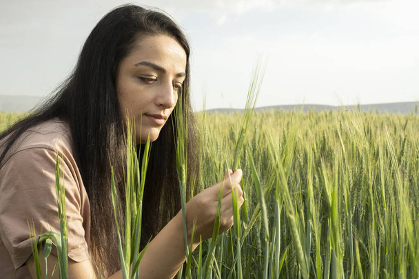 Agronomist woman farmer, modern millennial agronomist woman farmer in green wheat field. Business woman working in the field. Holding and checking wheat ear. Agricultural business concept idea. - Photo, Image