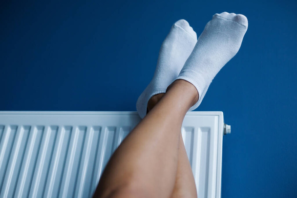 Женские ножки в носках нагреваются на радиаторе нагрева воды в комнате - Фото, изображение