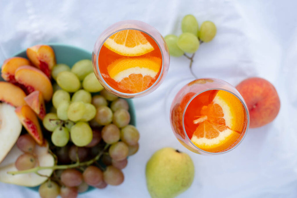 wine in glasses and with orange, grape, peach, pear. summer picnic - Fotoğraf, Görsel