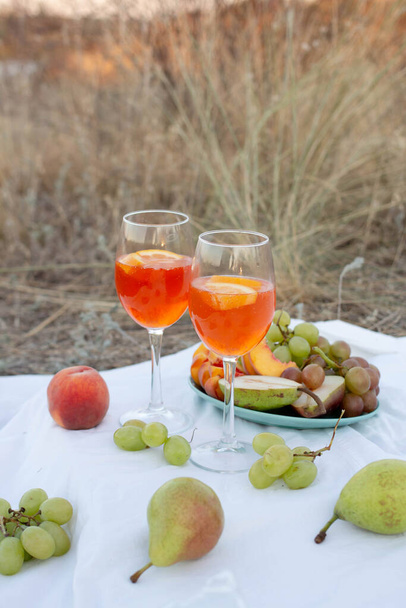 wine in glasses and with orange, grape, peach, pear. summer picnic - Foto, afbeelding