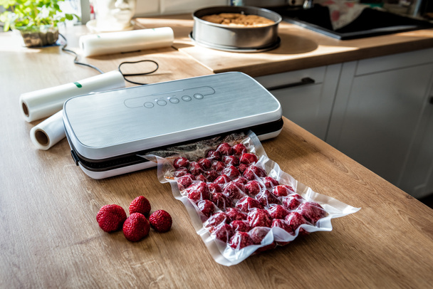 Vacuum strawberries packaging for long-term storage. They use of a vacuum sealer for long-term storage of products. Vacuum packing machine - Fotoğraf, Görsel