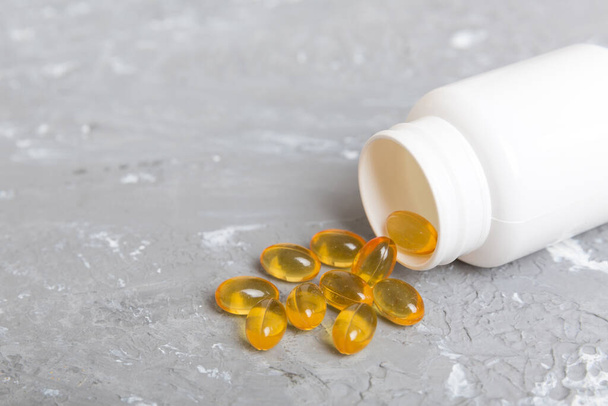 Omega-3 capsules lie in white bottle on a table background. Fish oil tablets top view. Biologically active additives. omega 6, omega 9, vitamin A, E, vitamin D, vitamin D3, evening primrose oil. - 写真・画像