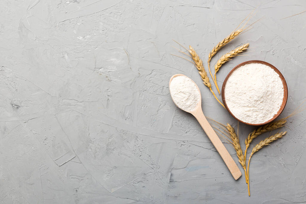 Flat lay of Wheat flour in wooden bowl with wheat spikelets on colored background. world wheat crisis. - Photo, Image