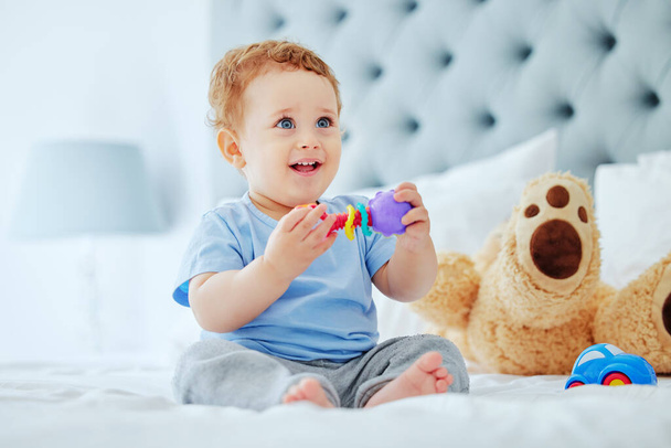 full length shot van een schattige kleine jongen spelen in zijn ouders slaapkamer thuis. - Foto, afbeelding