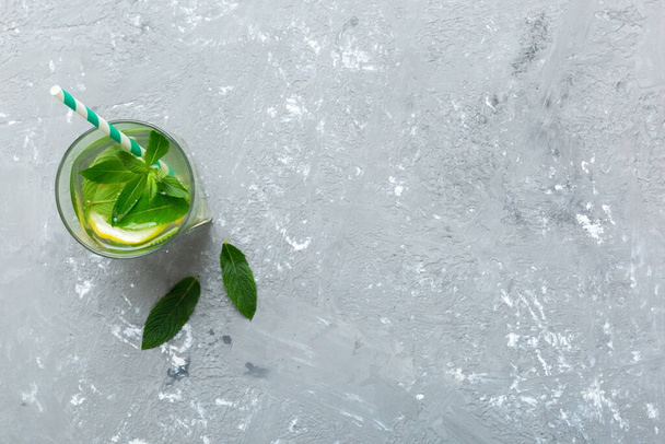 Caipirinha, Mojito cocktail, vodka or soda drink with lime, mint and straw on table background. Refreshing beverage with mint and lime in glass top view flat lay. - Photo, Image