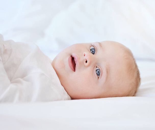 an adorable little baby boy lying on a bed at home. - Photo, image