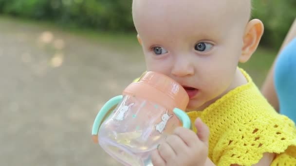 Portrait of a cute drinking little toddler girl. baby drinks from a baby cup. - Filmati, video