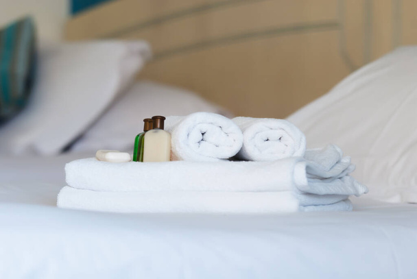 witte zuivere handdoeken op bed in het hotel met zeep en douchegel - Foto, afbeelding