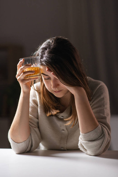 alcoholism, alcohol addiction and people concept - drunk woman or female alcoholic drinking whiskey at home - Foto, Bild