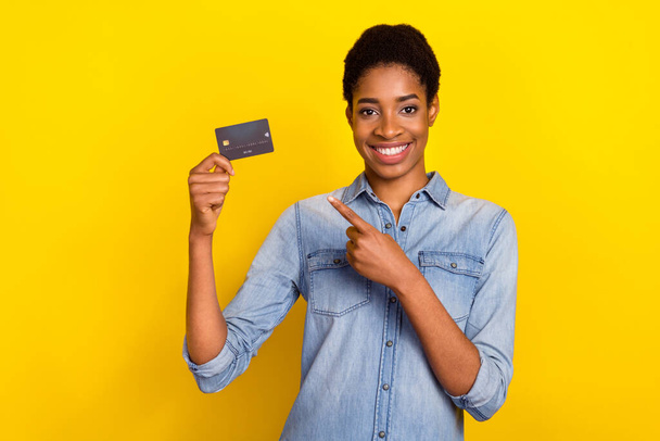 Photo of positive person indicate finger demonstrate plastic debit card isolated on yellow color background. - Zdjęcie, obraz