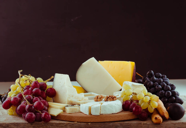 variace selektivního sýra na dřevěné desce s ovocem - Fotografie, Obrázek