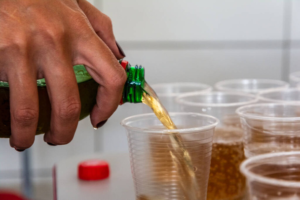 Soda being poured into a plastic cup to be drunk. Salvador, Bahia, Brazil. - 写真・画像