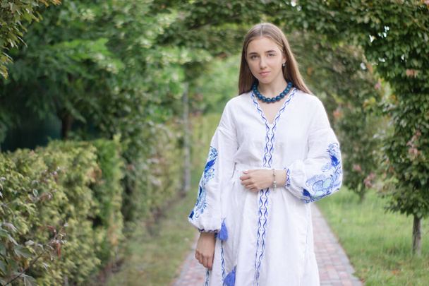 Portrait of young woman wearing blue national traditional embroidered shirt. pretty girl outdoor dressed in patriotic clothes. - Valokuva, kuva