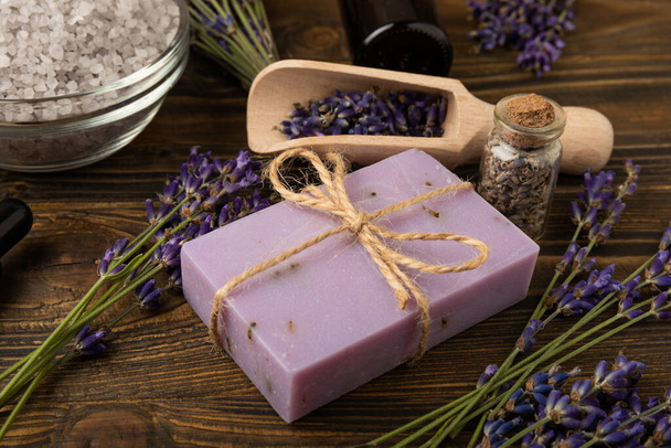 Lavender spa. Sea salt, lavender flowers and handmade soap. Natural herbal cosmetics with lavender flowers on brown texture wood.Spa and relaxation concept.Beauty treatments.Copy space. - Photo, image