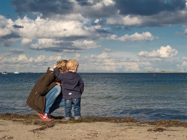 Мати і дитина на пляжі, дивлячись в бік моря восени
 - Фото, зображення