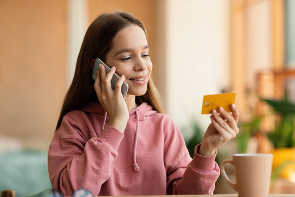 Счастливая кавказская девочка-подросток в повседневной одежде наводит порядок, разговаривает по мобильному телефону и держит кредитную карту, проводит время дома и за покупками в Интернете, копирует пространство - Фото, изображение