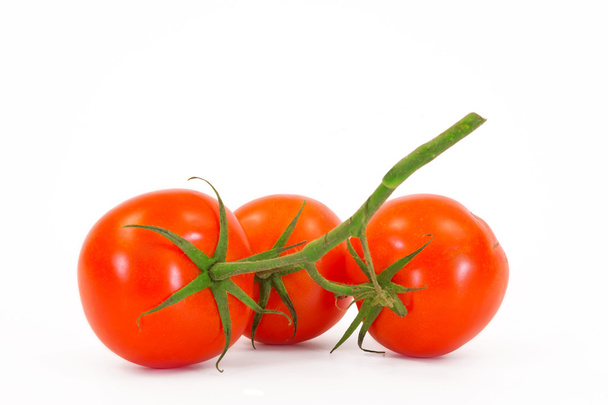 Three fresh tomatoes with green leaves isolated on white background - Photo, image