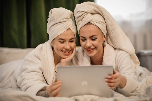 beautiful young women with cute daughter in bathrobe and towel smiling at camera in bedroom - Foto, Imagem
