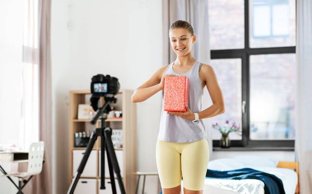 fitness, sport and video blogging concept - happy smiling teenage girl or blogger with camera on tripod and yoga block recording online class at home - Zdjęcie, obraz