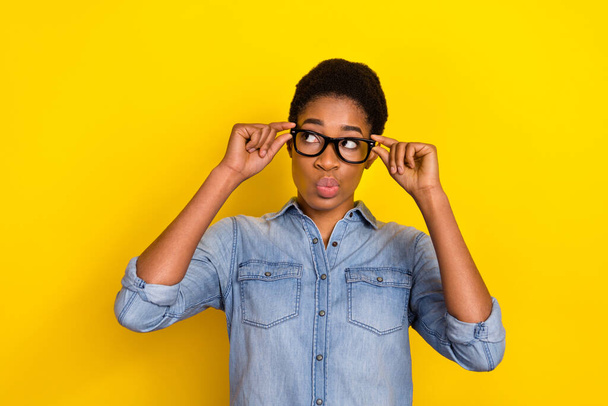 Portrait of minded person touch eyewear pouted lips look empty space hesitate isolated on yellow color background. - Foto, imagen