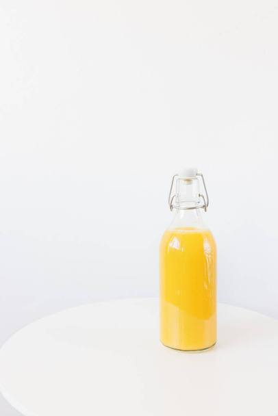 Fresh squeezed orange juice in retro bottle with stopper on table, white background. Healthy beverage for breakfast. Side view, copy space - Φωτογραφία, εικόνα