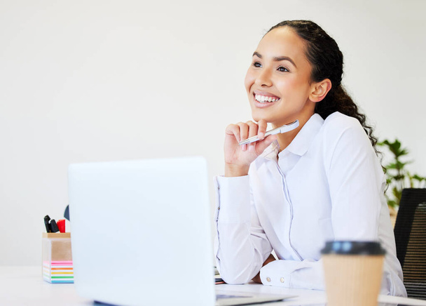 una giovane donna d'affari attraente seduta da sola in ufficio e dall'aspetto contemplativo mentre usa il suo portatile. - Foto, immagini