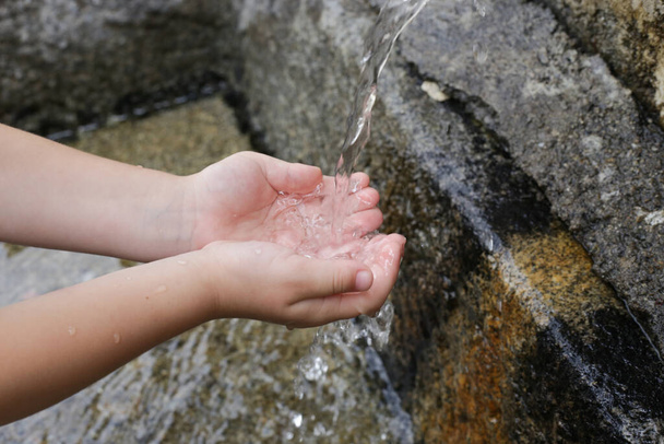 Bambina che beve acqua di sorgente pulita dal rubinetto esterno - Foto, immagini