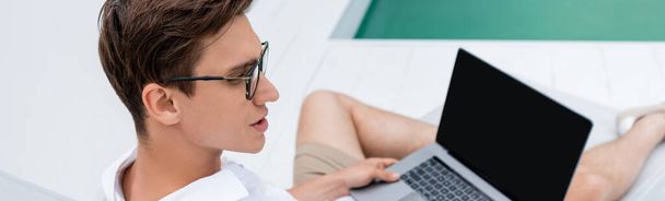 high angle view of man in eyeglasses near laptop with blank screen, banner - Φωτογραφία, εικόνα