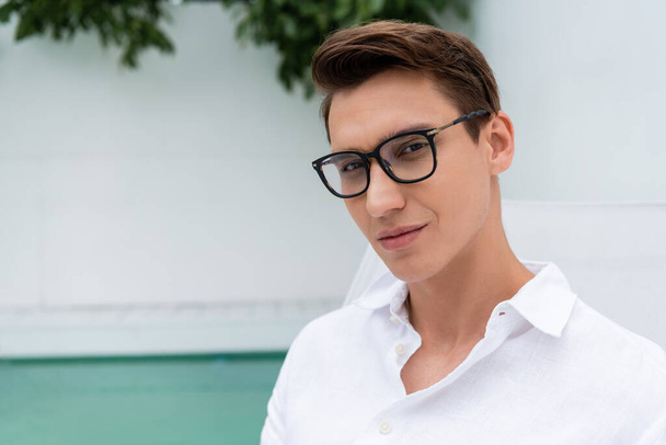 man in white shirt and eyeglasses looking at camera at poolside outdoors - Foto, imagen