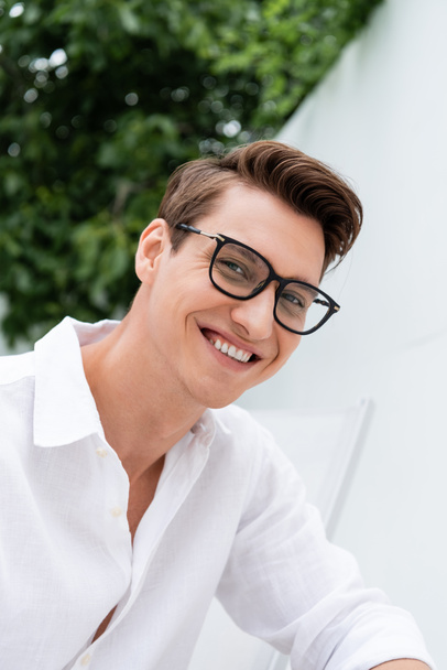happy man in white shirt and eyeglasses looking at camera outdoors - Foto, immagini