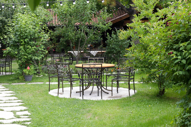 Столовые наборы в открытом кафе в красивом зеленом саду - Фото, изображение