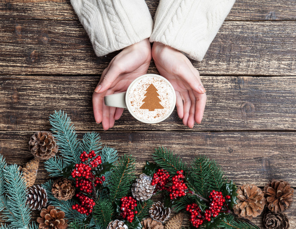 Kadın holding fincan kahve krem Noel ağacına bir tabl ile - Fotoğraf, Görsel