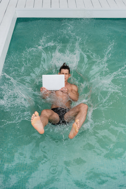 top view of freelancer jumping with laptop in pool with turquoise water  - Zdjęcie, obraz