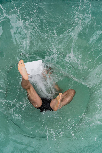 top view of man with laptop jumping in pool with turquoise water - Photo, Image