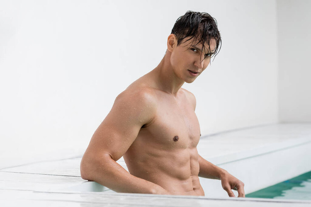 wet man with athletic torso looking at camera in pool - Foto, Bild