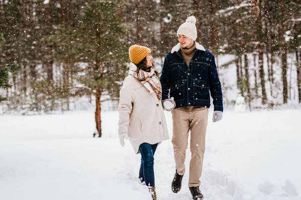people, love and leisure concept - happy smiling couple walking in winter forest - Foto, Imagen