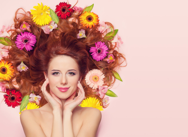 Gyönyörű vörös hajú lány virágok rózsaszín háttér - Fotó, kép