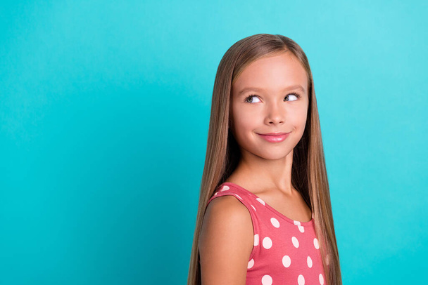 Photo of charming thoughtful small girl wear pink dress smiling looking empty space isolated turquoise color background. - 写真・画像
