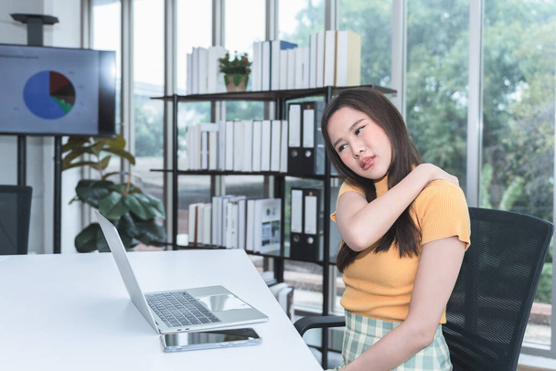 Aziatische zakenvrouw is moe, vermoeid en heeft schouderpijn van zitten en het gebruik van de computer voor een lange tijd, om zakenmensen en het syndroom van kantoor concept. - Foto, afbeelding