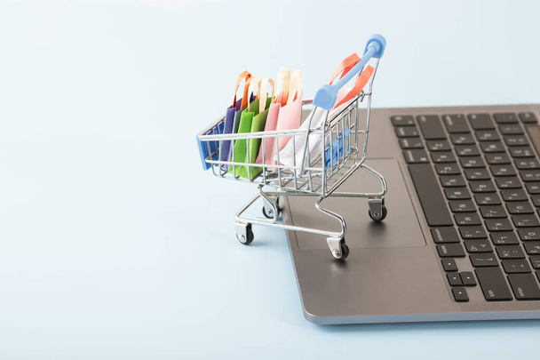 Online shopping concept. Shopping cart, small boxes, laptop on the desk. High quality photo - Foto, Imagen