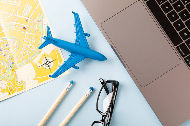 Área de trabalho com um mapa, café e um avião, sobre um fundo azul. Conceito de viagem. Foto de alta qualidade - Foto, Imagem