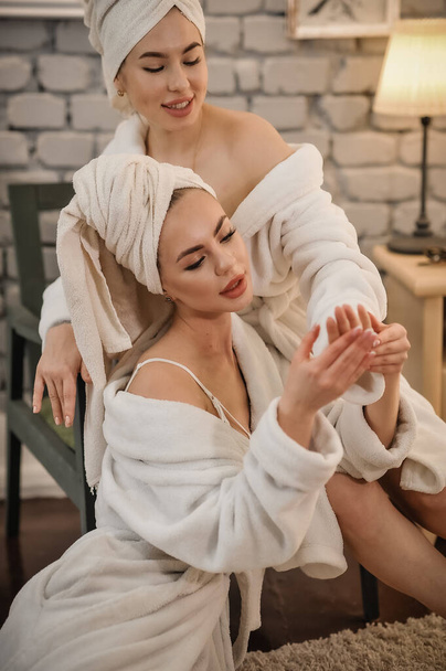 beautiful young woman in white bathrobe and towel lying on massage table in spa salon - Фото, изображение