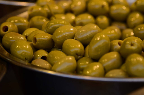 Appetizing olives in assortment. Green and black olives at a market in Tel Aviv. Large beautiful pickled olives. - 写真・画像